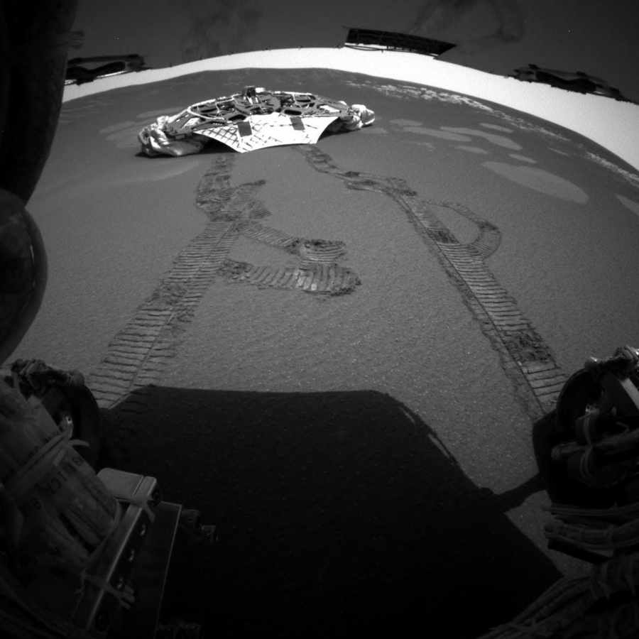 FILE - This photo released Thursday, Feb. 5, 2004 made by one of the rear hazard-avoidance cameras on NASA’s Opportunity rover, shows Opportunity’s landing platform, with freshly made tracks leading away from it. Opportunity rolled about 11 feet on Thursday, the first day it has moved since it left the lander on Saturday. Engineers commanded Opportunity to turn slightly during the drive, to test how it steers while rolling through the martian soil.