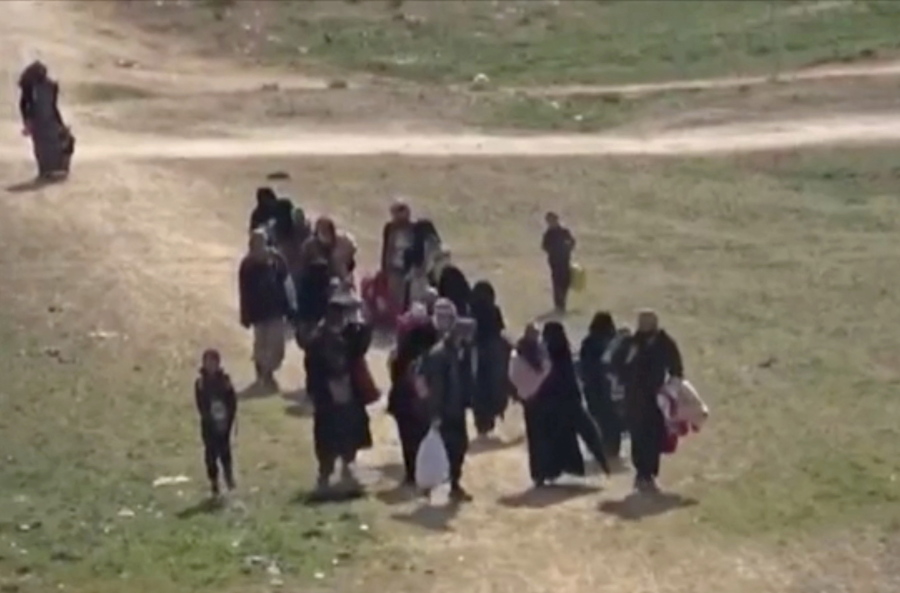 In this image from video provided by Hawar News Agency ANHA, an online Kurdish news service, civilians flee fighting Sunday near Baghouz, Syria. Fierce fighting was underway Monday between U.S.-backed Syrian forces and the Islamic State group in eastern Syria.