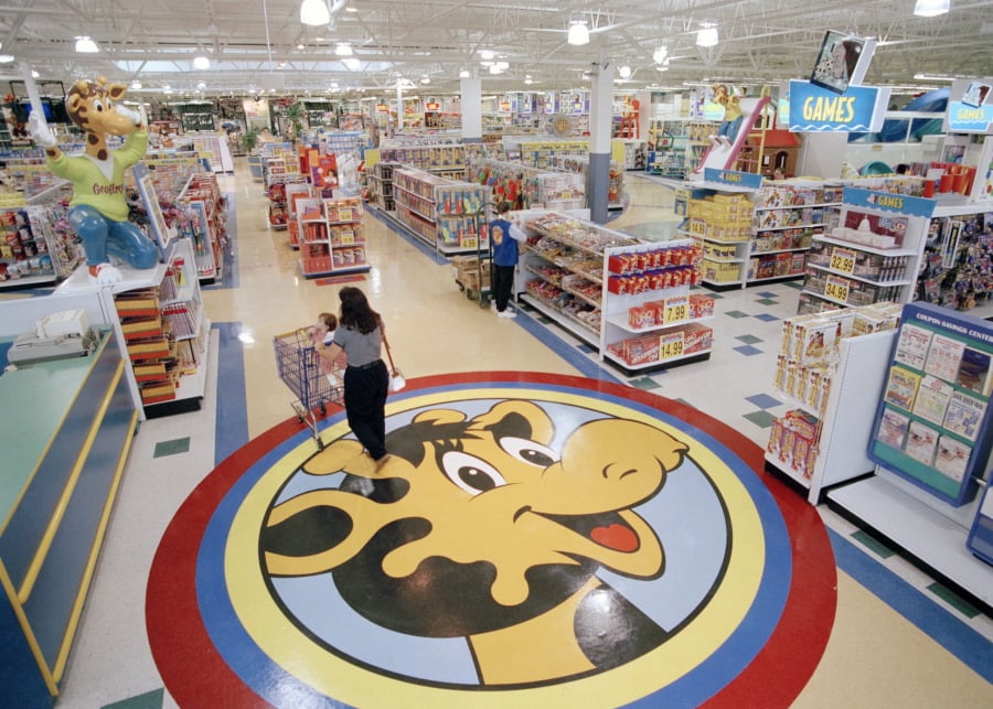In this July 30, 1996, file photo, a woman pushes a shopping cart over a graphic of Toys R Us mascot Geoffrey the giraffe at the Toys R Us store in Raritan, N.J. Richard Barry, a former Toys R Us executive and now CEO of the new company called Tru Kids Inc., is exploring freestanding stores, shops within existing stores as well as e-commerce. Tru Kids, owned by former investors of Toys R Us, will manage the Toys R Us, Babies R Us and Geoffrey brands.s.