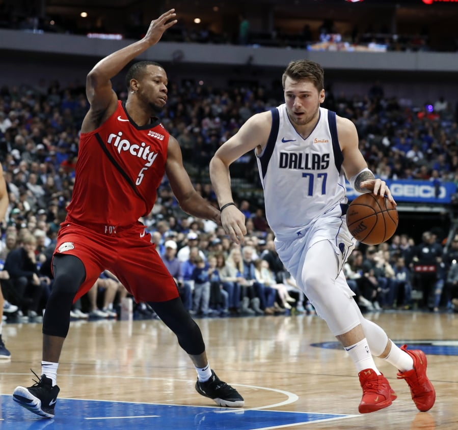 Portland Trail Blazers’ Rodney Hood (5) defends as Dallas Mavericks forward Luka Doncic (77) drives to the basket for a shot in the first half of an NBA basketball game in Dallas, Sunday, Feb. 10, 2019.