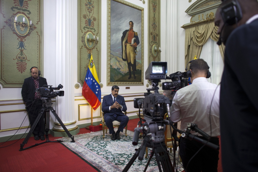 Venezuela’s President Nicolas Maduro speaks during an interview with The Associated Press at Miraflores presidential palace, where a painting of independence hero Simon Bolivar hangs, in Caracas, Venezuela, Thursday, Feb. 14, 2019. Maduro is inviting a U.S. special envoy to come to Venezuela after revealing during the interview that his foreign minister recently held secret meetings with the U.S. official in New York.
