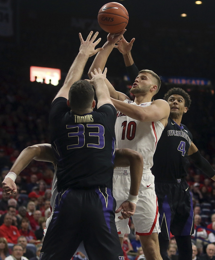 Arizona forward Ryan Luther (10) jumps for the basket while defended by Washington forward Sam Timmins (33) and guard Matisse Thybulle (4) in the first half of an NCAA college basketball game in Tucson, Ariz., Thursday, Feb. 7, 2019.