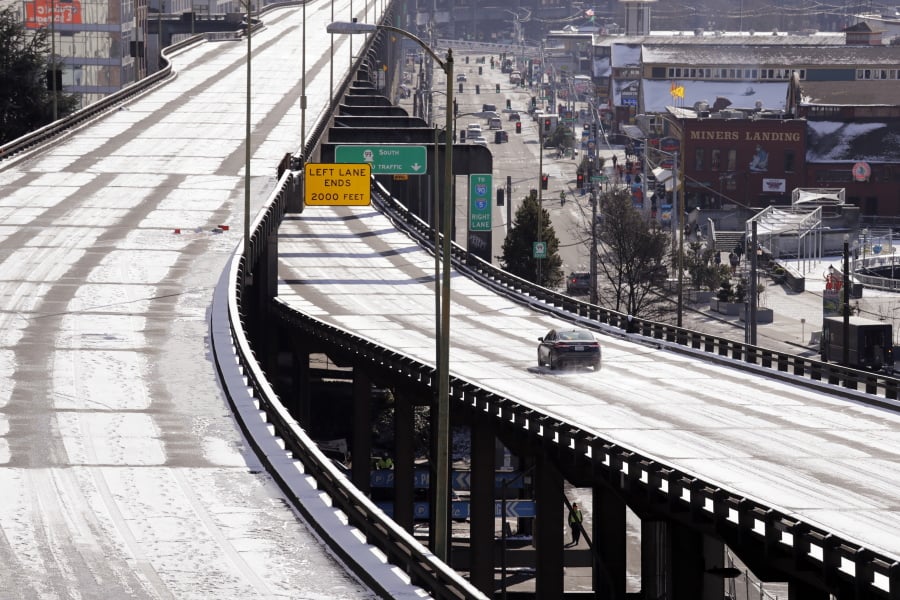 A car belonging to a state agency drives over a light coating of snow on the otherwise closed Alaskan Way viaduct in near-freezing weather Tuesday, Feb. 5, 2019, in Seattle. The highway closed several weeks earlier, replaced with a two-mile tunnel running under downtown Seattle and which opened a day earlier. Winter weather closed schools and disrupted travel across much of the West, with ice and snow stretching from Seattle to Arizona. The Pacific Northwest shivered Tuesday under colder-than-normal conditions as snow and treacherous conditions led to another day of school closures.
