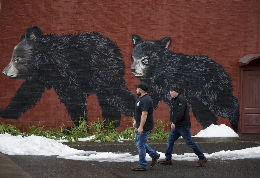 Washougal residents Shaun Humes, left, and Al Seaman stroll past a festive mural on their way to lunch in downtown Washougal on Feb. 11 as leftover snow melts nearby. The city is No. 7 on a list of the state’s safest.