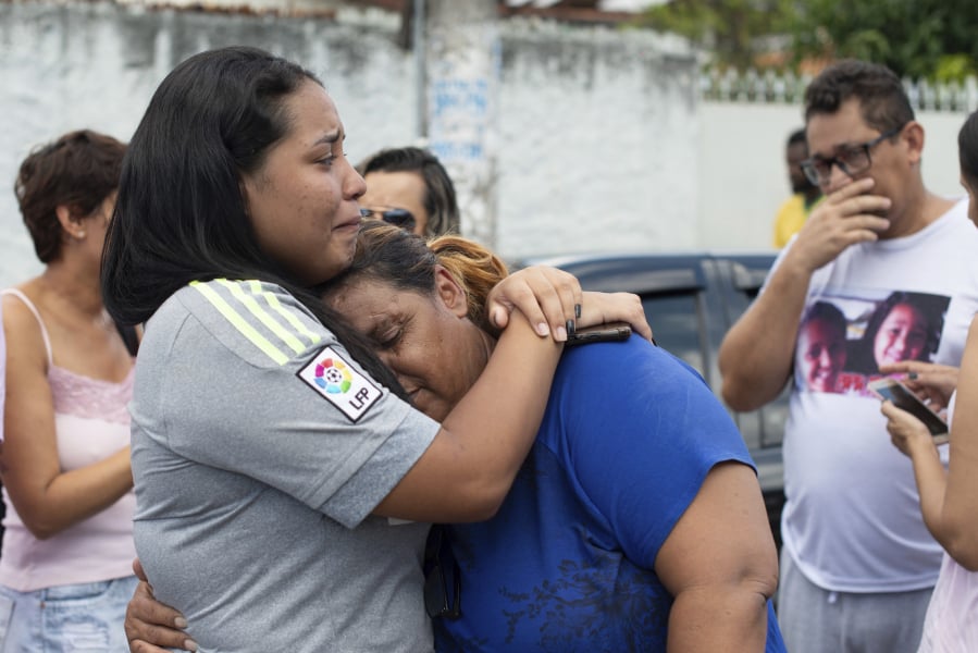 A woman is comforted Wednesday outside Raul Brasil State School in Suzano, Brazil, after a shooting that has left at least eight people dead.