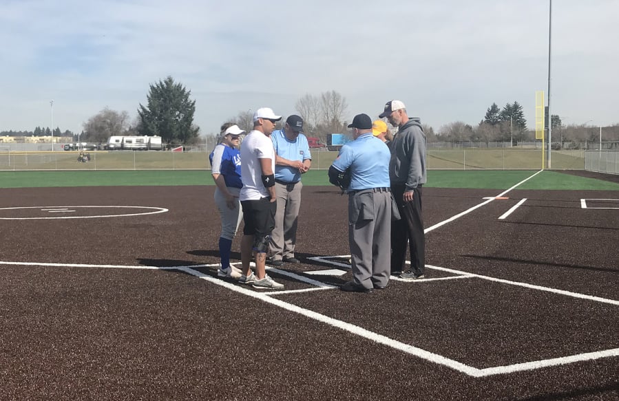 Coaches from La Center and Hudson's Bay meet with umpires before the second game of Saturday's Trapper Softball Classic.
