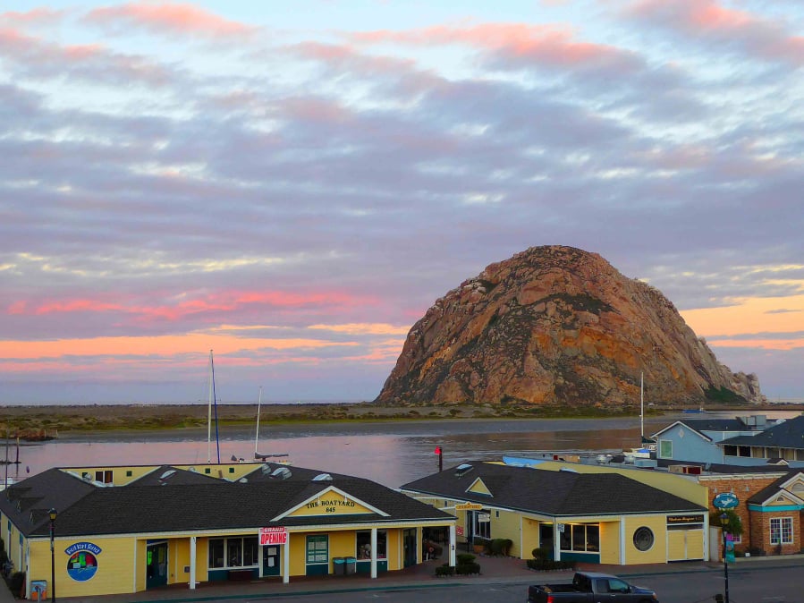 Morro Rock stands silhouetted against the colors of the dawn sky in California.