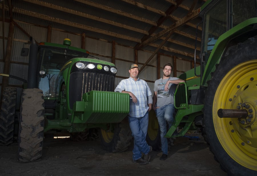 Grant Cummins and his son Parker are seen March 15 with tractors they use to farm mint near Murtaugh, Idaho.