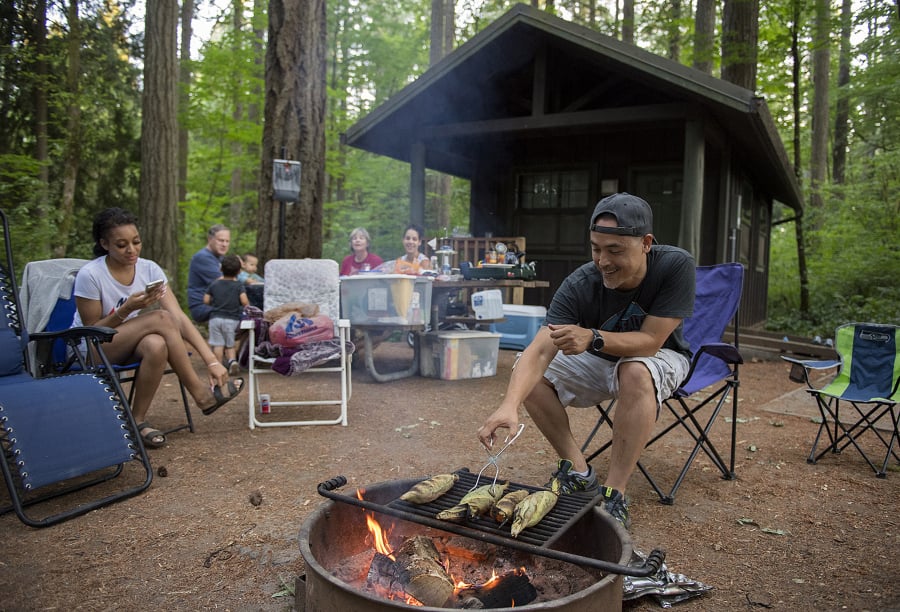Ray Young, right, of Pacific grills up some fresh corn July 17, 2018, while cooking for members of his family at Battle Ground Lake State Park. The family’s dinner also included smoked beans and smoked bratwursts on a bun.