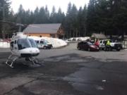 A helicopter and search-and-rescue personnel are seen at Marble Mountain Sno-Park as part of a rescue effort for two men who were stuck on Mount St. Helens overnight Sunday.