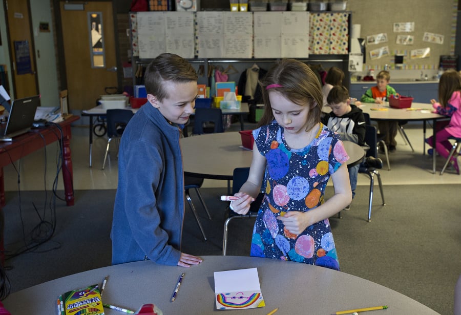 Anthony Moro-Baxter, 10, left, a former student at South Ridge Elementary School, offers encouragement as he stops by the work station of first-grader Delaney Baylous, 7, while she creates a card that will be given to a patient at Randall Children’s Hospital in Portland.
