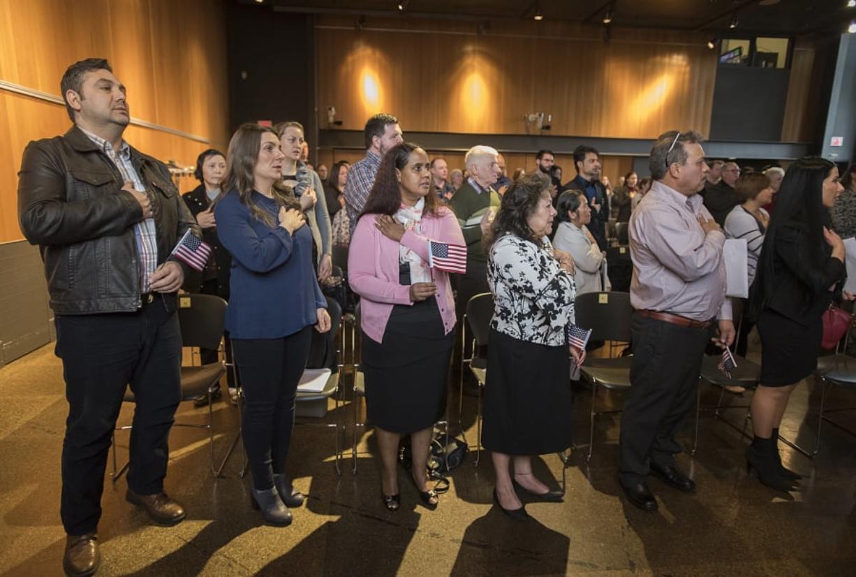 New American citizens recite the Pledge of Allegiance during a naturalization ceremony Thursday morning at Vancouver Community Library. They also recited the oath of allegiance, in which they gave up loyalty to their countries of origin and became U.S. citizens.