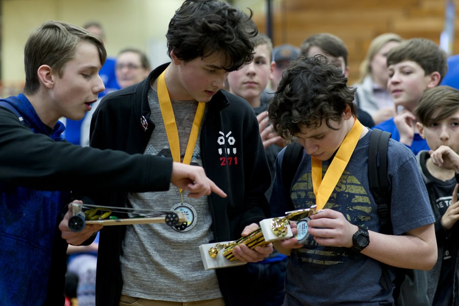 Nate McConnell, from left, interacts with classmates Aran O’Day and Mason McCarty as the teammates study their second-place trophy during the Solar Car Challenge at Hudson’s Bay High School Saturday in Vancouver. The challenge is a mixture of a science fair and pinewood derby, where teams present their car designs and race.
