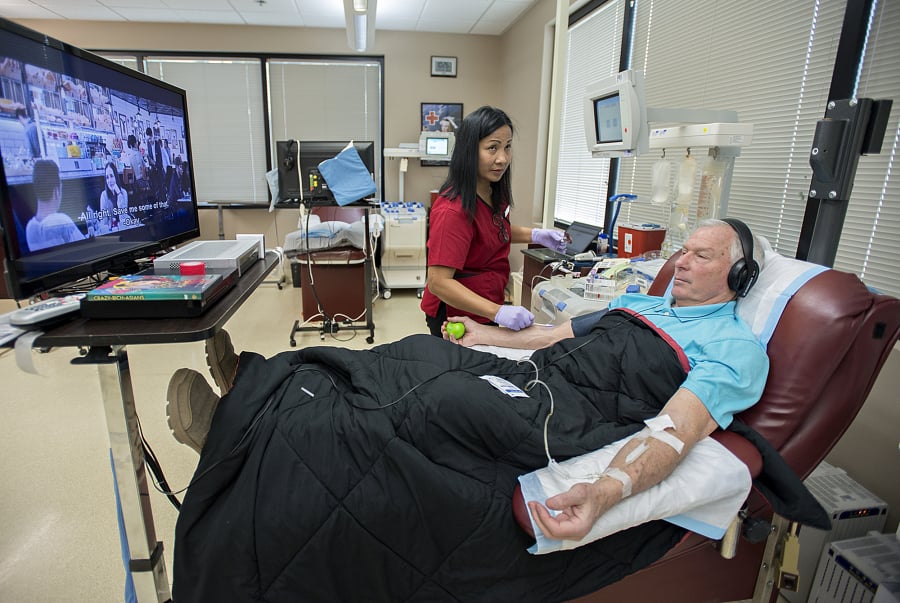 Phlebotomist Sotheary Chet, center, works with platelet donor John Reinhardt of Battle Ground at the American Red Cross Blood Donor Center in Vancouver. Reinhardt, a regular platelet donor, decided to watch “Crazy Rich Asians” over the two-hour donation process. Platelets, which have a shelf life of five days, are mainly used for trauma injuries.