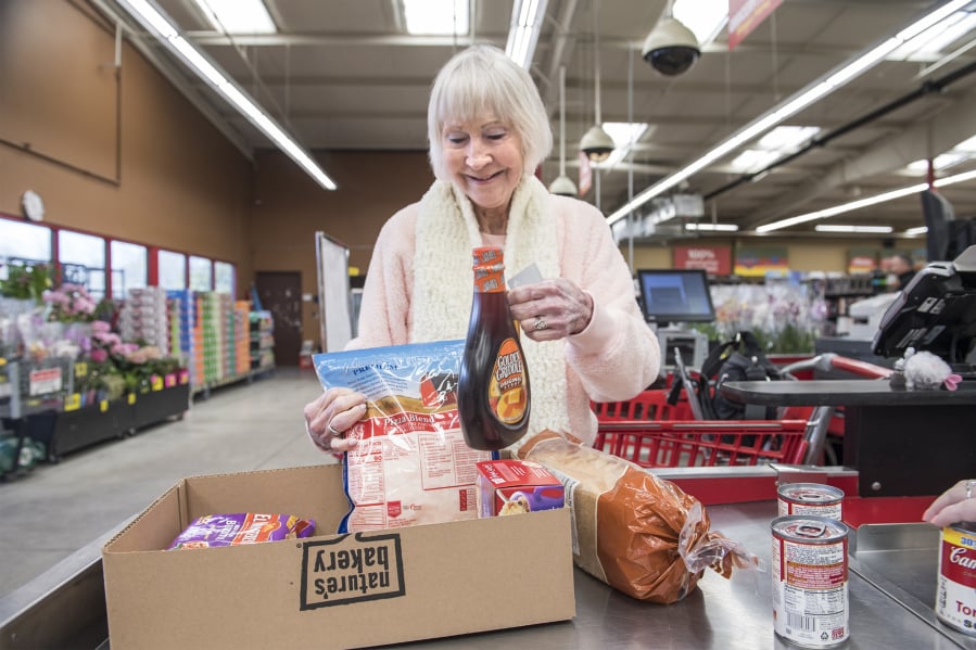 Christina Brown of Vancouver fills a box with groceries while checking out at the Vancouver Grocery Outlet. The store eliminated single-use plastic bags on March 1 and now offers boxes for customers who did not bring reusable bags. “I’m pretty glad,” Brown said.