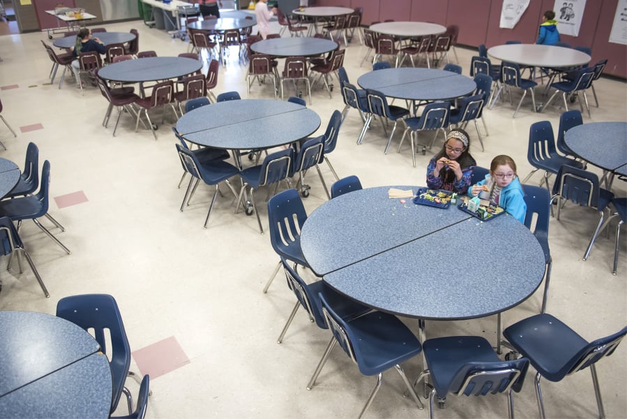 Fourth-graders Suhana Gandhi, left, and Vendetta Lee Jones, eat lunch in the cafeteria of Chinook Elementary School on Thursday after taking extra time while their classmates went to recess. At top, second-graders Arielle Hess, left, and Amelya Schei laugh during lunch.