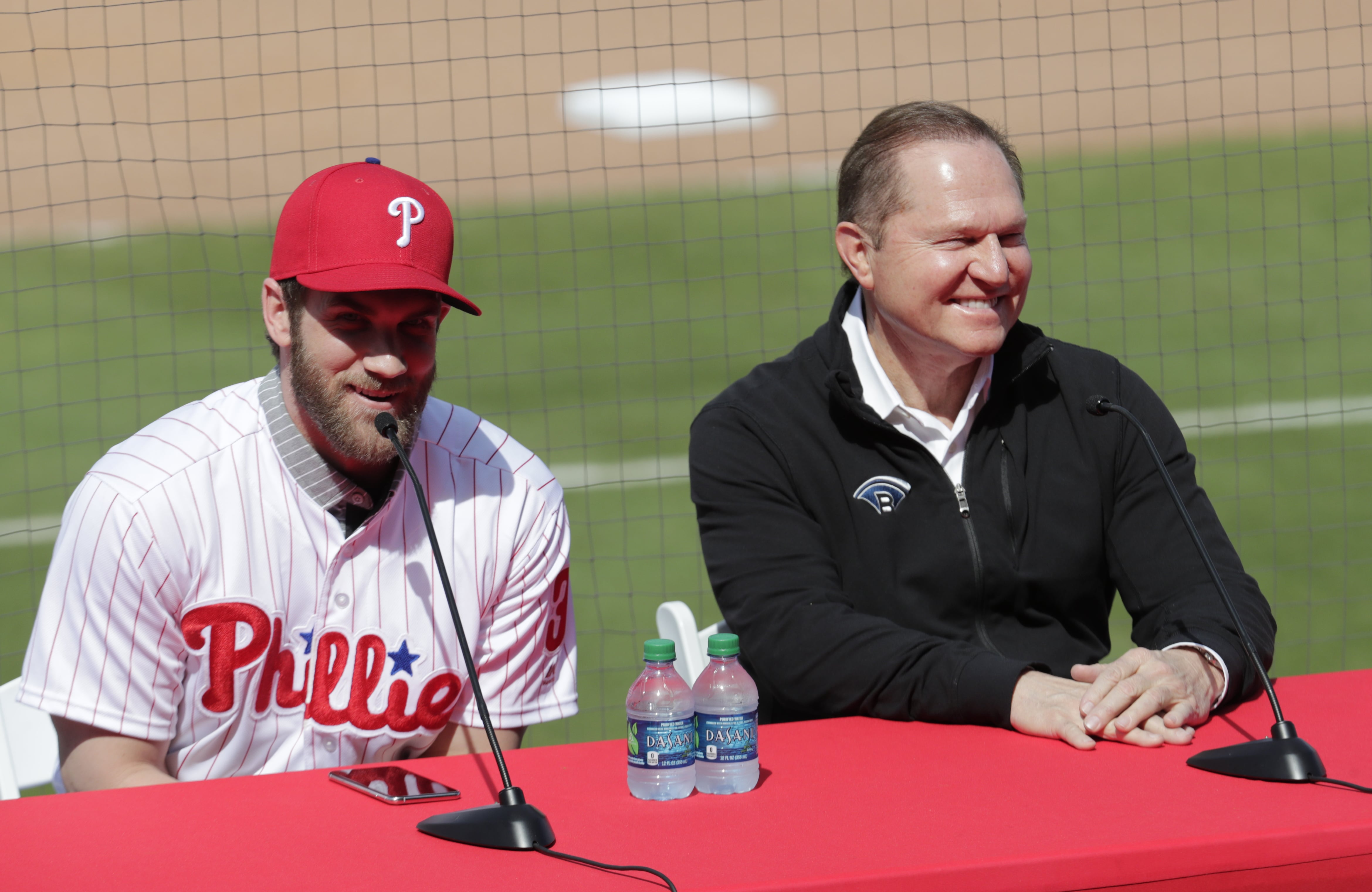 Bryce Harper, left, speaks during a news conference at the Philadelphia Phillies spring training baseball facility as his agent Scott Boras looks on, Saturday, March 2, 2019, in Clearwater, Fla. Harper and the Phillies agreed to a $330 million, 13-year contract, the largest deal in baseball history.