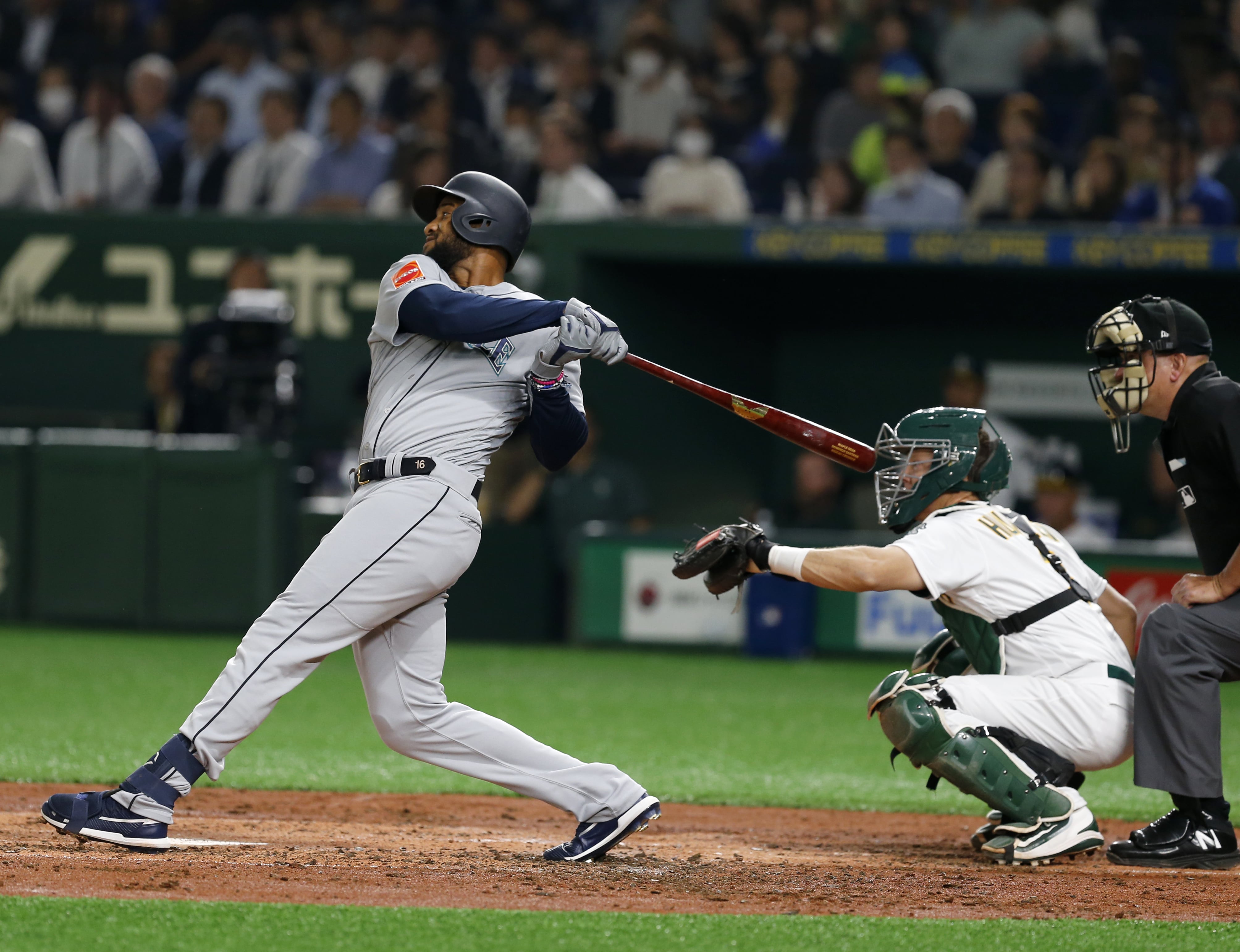 Seattle Mariners' Domingo Santana hits a grand slam off Oakland Athletics starter Mike Fiers in the third inning of Game 1 of their Major League opening series baseball game at Tokyo Dome in Tokyo, Wednesday, March 20, 2019. Athletics catcher is catcher Nick Hundley.
