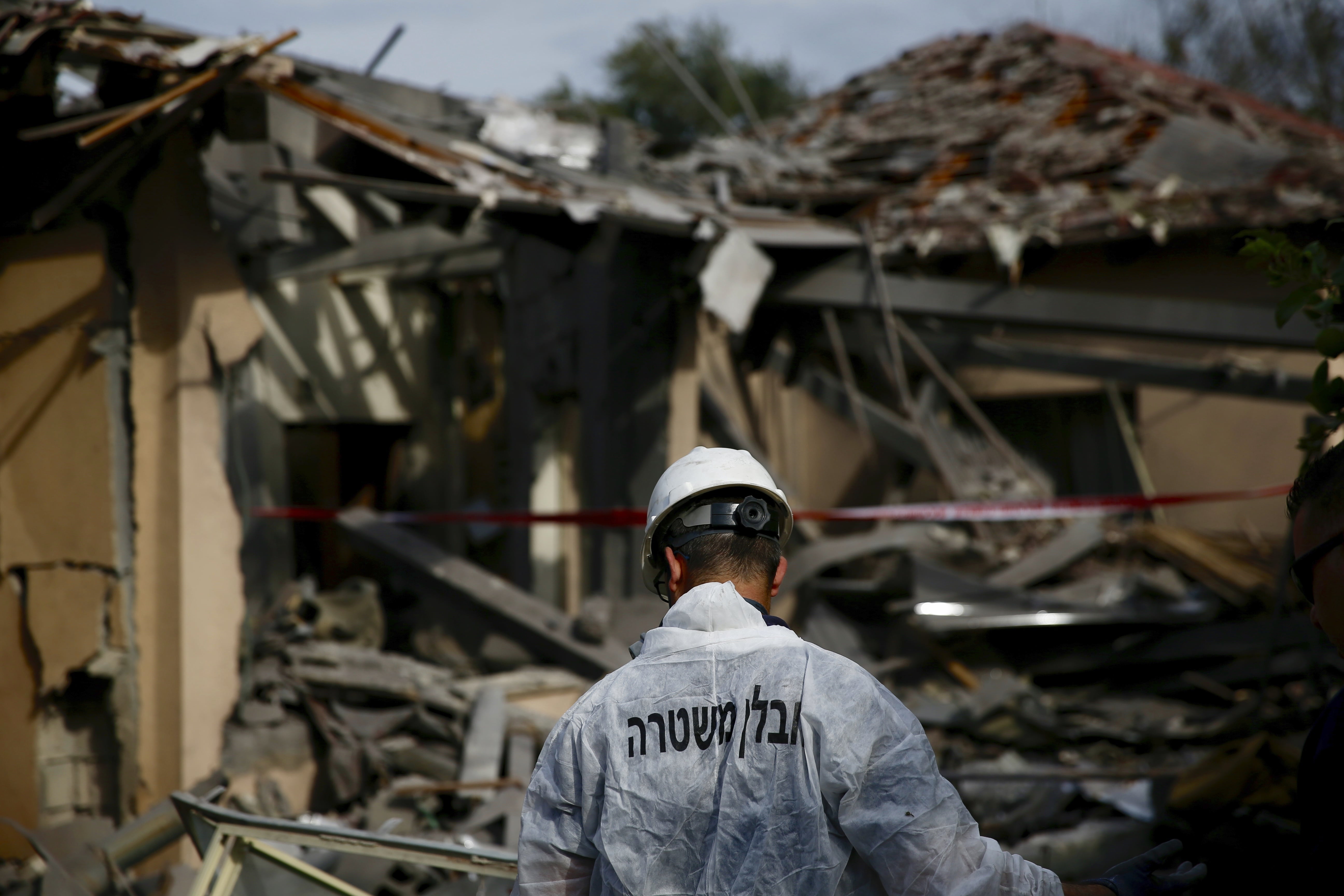 An Israeli police officer inspects the damage to a house hit by a rocket in Mishmeret, central Israel, Monday, March 25, 2019. An early morning rocket from the Gaza Strip struck a house in central Israel on Monday, wounding several people, including one moderately, an Israeli rescue service said, in an eruption of violence that could set off another round of violence shortly before the Israeli election.