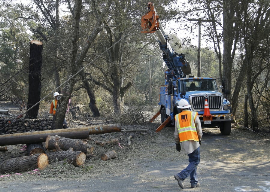 FILE - In this Oct. 18, 2017 file photo, a Pacific Gas & Electric crew works on replacing poles destroyed by wildfires in Glen Ellen, Calif. A U.S. judge in San Francisco overseeing a criminal case against Pacific Gas & Electric Co. is scaling back his proposals to prevent the utility’s equipment from causing more wildfires. Judge William Alsup said in an order late Tuesday, March 5, 2019, that he’s now considering making PG&E comply with targets in a wildfire mitigation plan that the company submitted to California regulators.