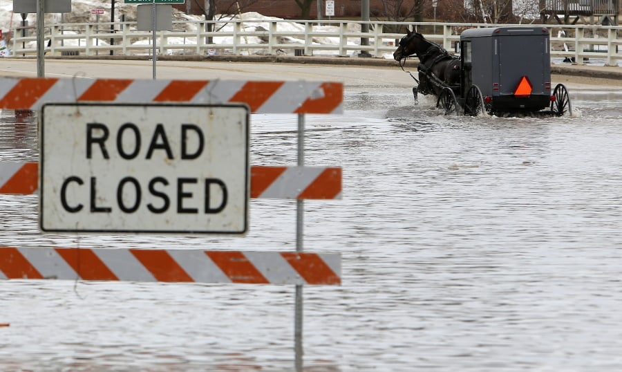 A man works his way through a flooded Galena Street as the Pecatonica River continues to rise in Darlington, Wis., Thursday, March 14, 2019. The National Weather Service has issued a flood warning or flood watch for about two-thirds of the state.