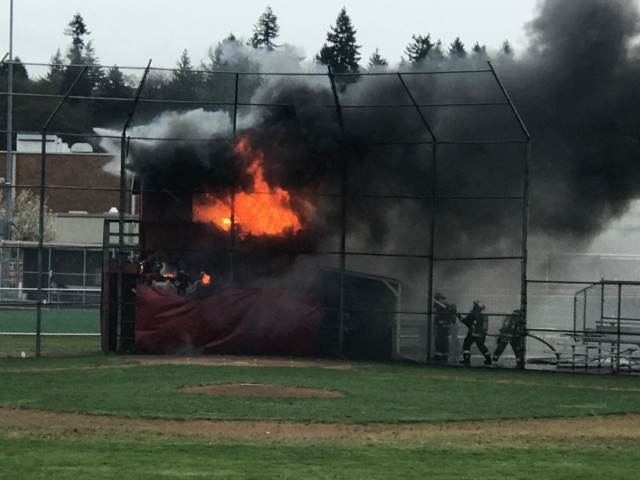 Firefighters extinguish a blaze Wednesday afternoon at a baseball score tower at Fort Vancouver High School.