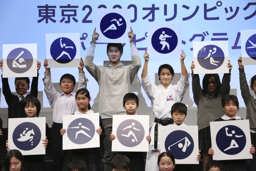 Rio Olympics athletics silver medallist Shota Iizuka, top center left, karate athlete Kiyo Shimizu, top center right, and elementary school students pose with pictograms of Tokyo 2020 Olympic sports events during a celebration to mark 500 days to go, in Tokyo, Tuesday, March 12, 2019. Organizers marked the milestone on Tuesday, unveiling the stylized pictogram figures for next year’s Tokyo Olympics.