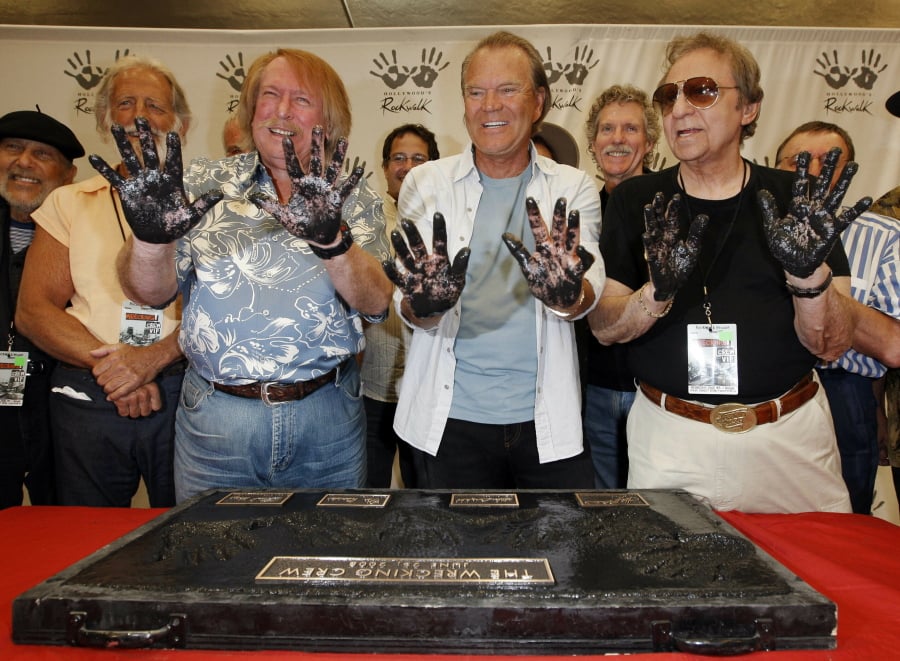 FILE - In this June 25, 2008, file photo, Don Randi, from left, Glen Campbell and Hal Blaine, representing session musicians known as The Wrecking Crew, hold up their hands after placing them in the cement following the induction ceremony for Hollywood’s RockWalk in Los Angeles. Drummer Blaine, who played on many of the biggest hits in music history, has died. Blaine’s son-in-law Andy Johnson tells The Associated Press that Blaine died of natural causes Monday, March 11, 2019, at his home in Palm Desert, California. He was 90.