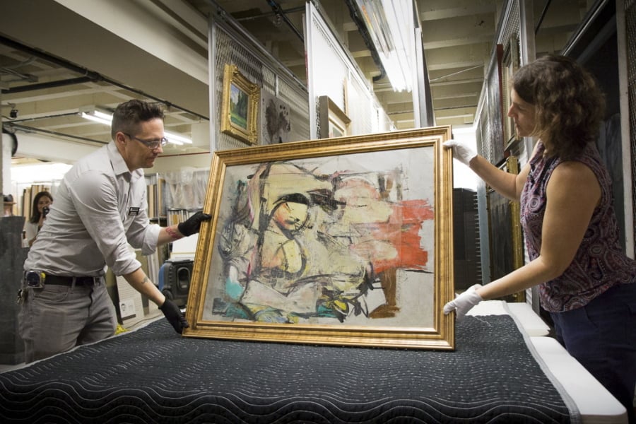 This August 2017 photo shows “Woman-Ochre,” by Willem de Kooning, is readied for examination in August 2017 by University of Arizona Museum of Art staff Nathan Saxton, left, and Kristen Schmidt in Tucson, Ariz.