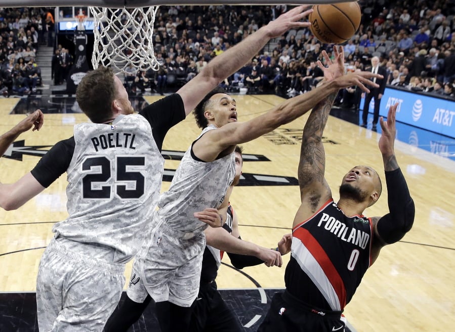 Portland Trail Blazers guard Damian Lillard (0) is blocked as he tries to score against San Antonio Spurs center Jakob Poeltl (25) and guard Derrick White, center, during the second half of an NBA basketball game in San Antonio, Saturday, March 16, 2019. San Antonio won 108-103.