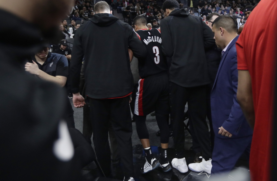 Portland Trail Blazers guard CJ McCollum (3) is helped off the court after he was injured on a play during the second half of an NBA basketball game against the San Antonio Spurs, in San Antonio, Saturday, March 16, 2019. San Antonio won 108-103.