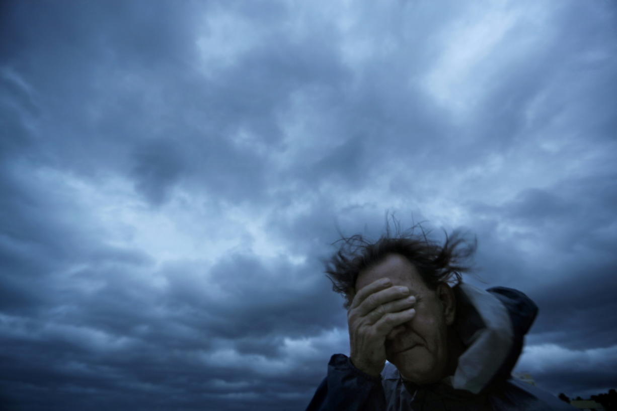 FILE - In this Friday, Sept. 14, 2018 file photo, Russ Lewis covers his eyes from a gust of wind and a blast of sand as Hurricane Florence approaches Myrtle Beach, S.C. According to a scientific report from the United Nations released on Wednesday, March 13, 2019, climate change, a global major extinction of animals and plants, a human population soaring toward 10 billion, degraded land, polluted air, and plastics, pesticides and hormone-changing chemicals in the water are making the planet an increasing unhealthy place for people.