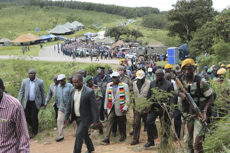 Zimbabwean President Emmerson Mnangagwa, center with scarf, visits Chimanimani about 600 km south east of Harare, Zimbabwe, Wednesday March 20, 2019. Mnangagwa visited a part of Chimanimnani affected by cyclone Idai and promised assitance in the form of food and rebuilding of homes. Hundreds are dead, many more missing and thousands at risk from massive flooding in Mozambique, Malawi and Zimbabwe caused by Cyclone Idai.