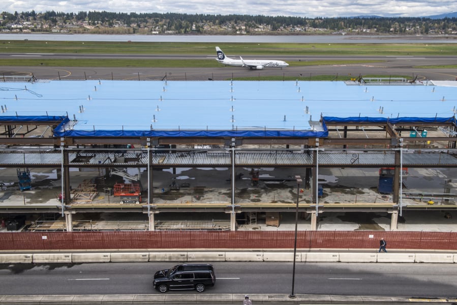 An Alaska Airlines jet taxis behind the Concourse E extension at Portland International Airport. The project, scheduled for completion in June 2020, is part of a $2 billion package of PDX improvements.