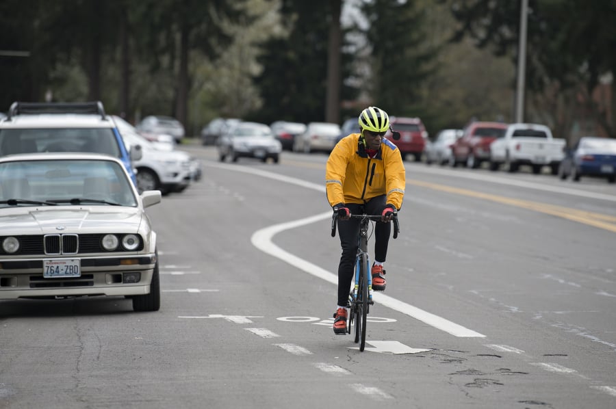 Cyclist Maurice Goudeau of Vancouver cruises past Clark College as he approaches the intersection of Fort Vancouver Way and McLoughlin Boulevard in the bike lane last week. At top, a sign near Clark College offers directions for people on two wheels as well as four.