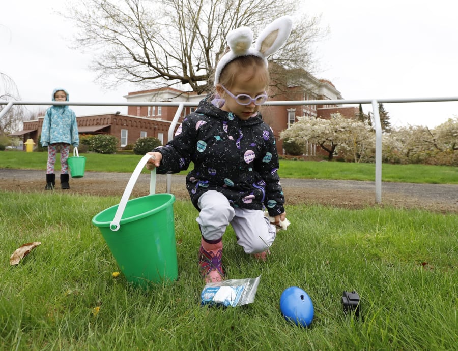 Stella Childers, 3, of Vancouver stoops for a beeping egg during an Easter egg hunt for visually impaired children. Visually impaired kids, such as her younger brother, and their sighted siblings participated.