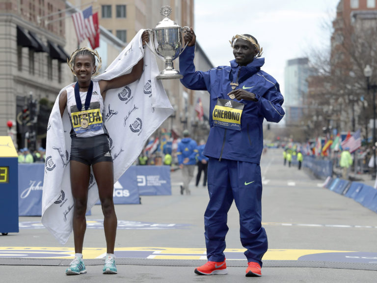 Worknesh Degefa, left, of Ethiopia, winner of the women's division, and Lawrence Cherono, right, of Kenya, winner of the men's division of the 123rd Boston Marathon, hold the trophy at the finish line on Monday, April 15, 2019, in Boston.