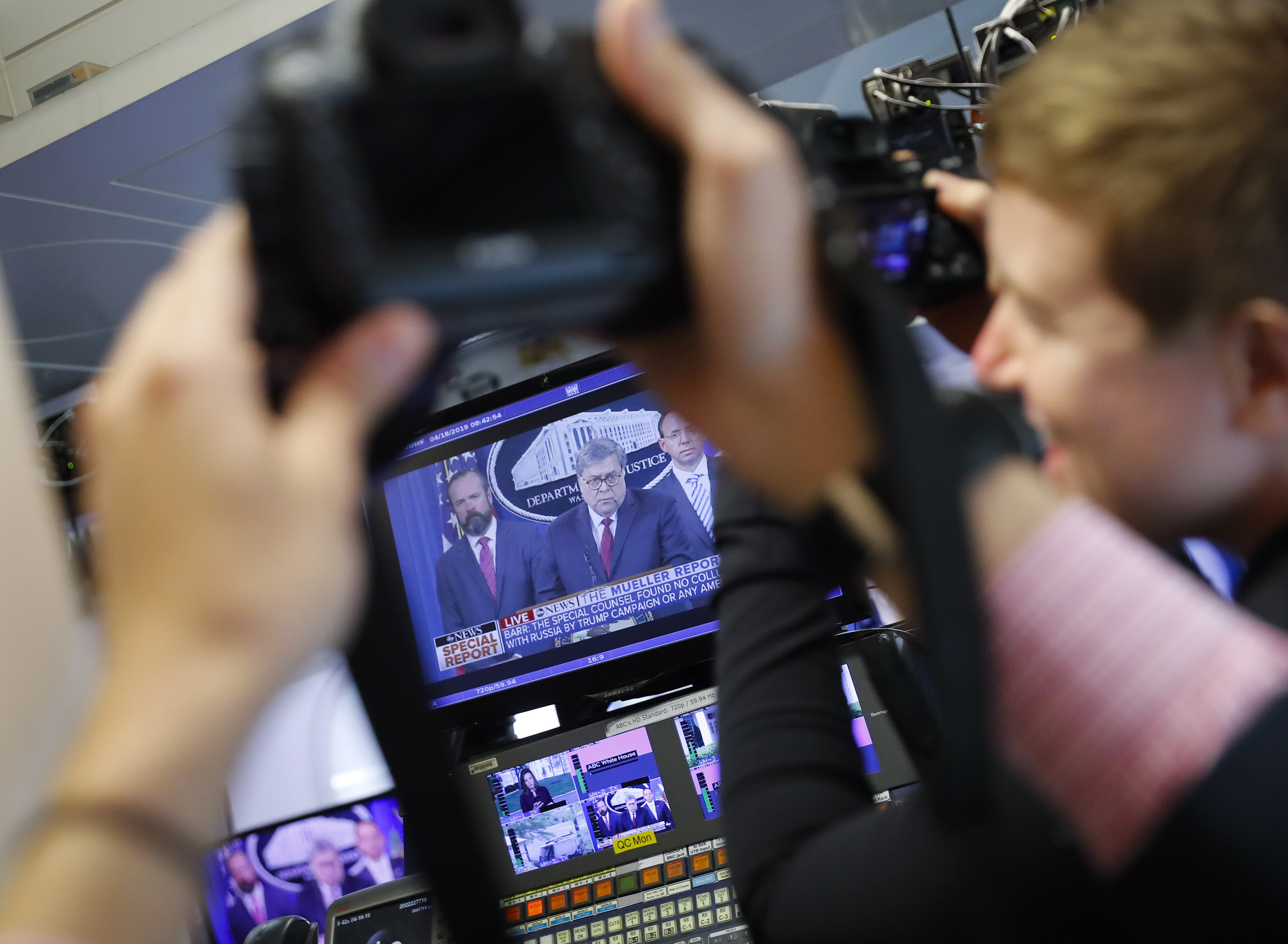 Journalists take photographs of the television broadcast monitors in the press room of the White House in Washington of Attorney General William Barr speaks alongside Deputy Attorney General Rod Rosenstein, right, and Deputy Attorney General Ed O'Callaghan, rear left, about the release of a redacted version of special counsel Robert Mueller's report April 18, 2019, Thursday, April 18, 2019, in Washington.