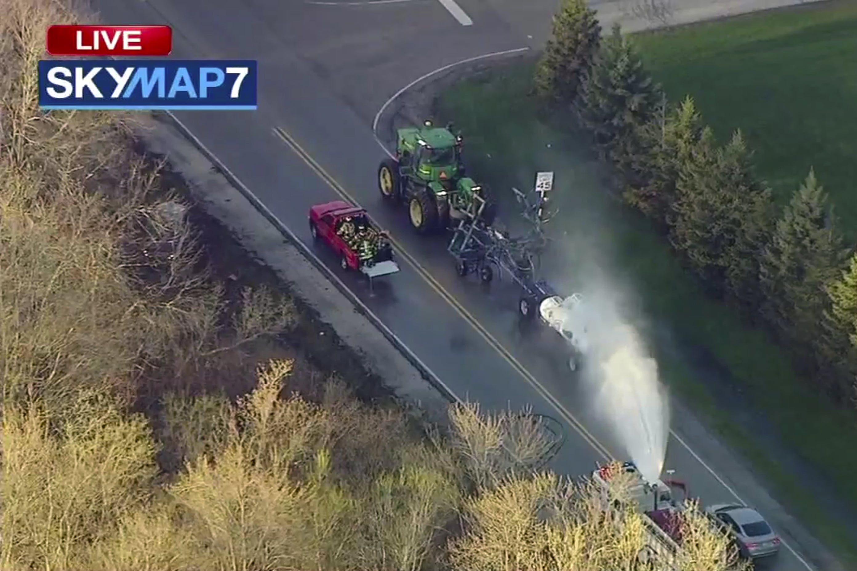 A fire engine sprays water on a container of the chemical that farmers use for soil after after anhydrous ammonia leaked Thursday, April 25, 2019, in Beach Park, Ill. Authorities say dozens of people have been taken to hospitals after anhydrous ammonia leaked from containers that a tractor was pulling in the Chicago suburb.