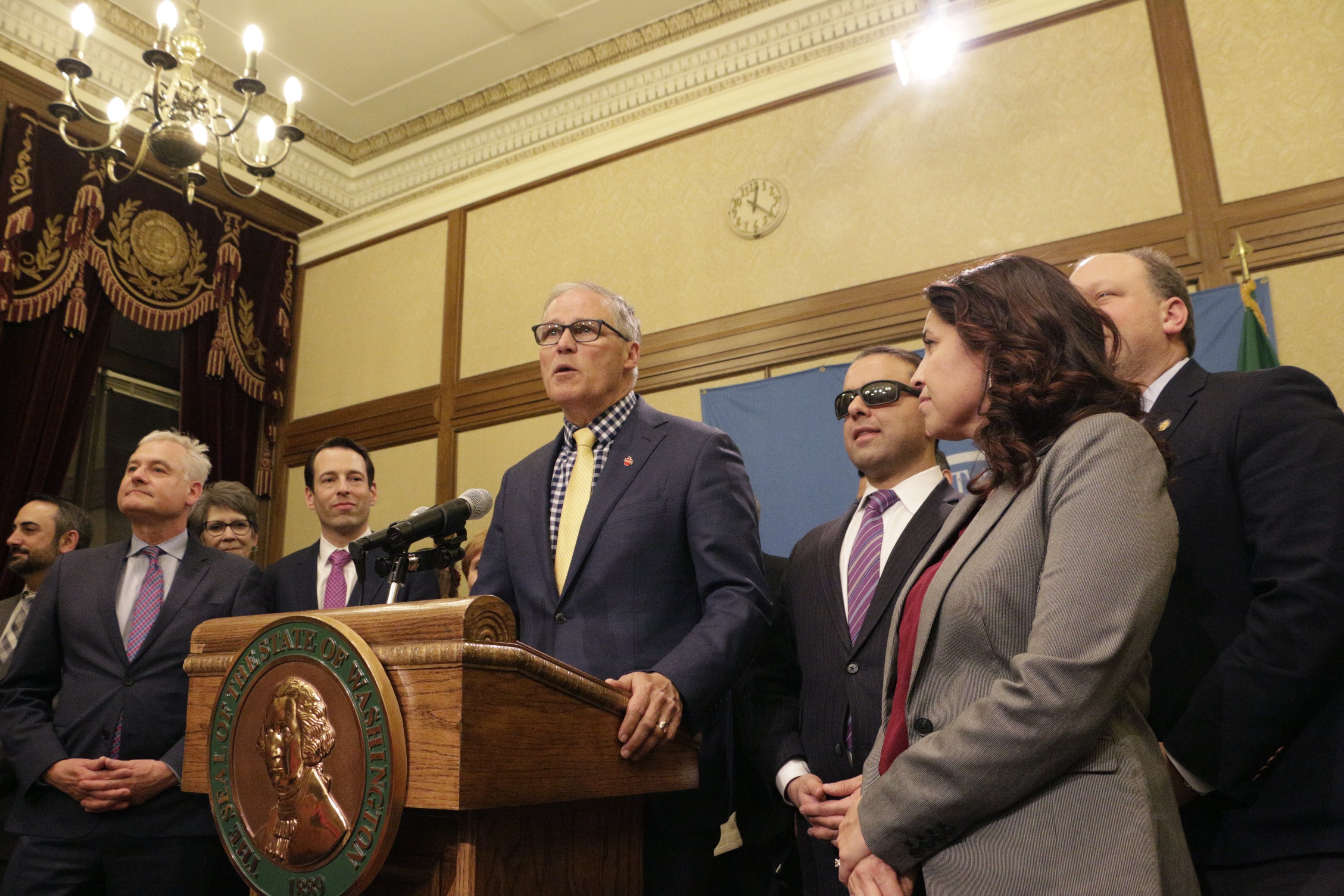 Gov. Jay Inslee, surrounded by Democratic lawmakers from the Senate and House, talks to the media early Monday morning following the Washington Legislature adjourning its 105-day legislative session in Olympia, Wash. Lawmakers passed a new, two-year budget before adjourning for the year.