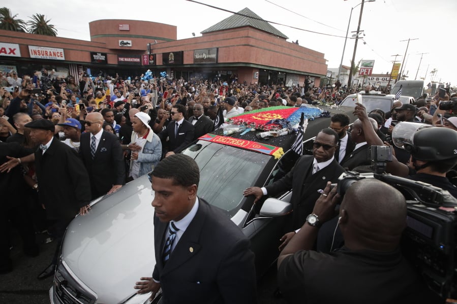 People watch as a hearse carrying the casket of slain rapper Nipsey Hussle passes Hussle’s clothing store The Marathon, Thursday, April 11, 2019, in Los Angeles. Hussle’s casket, draped in the flag of his father’s native country, Eritrea in East Africa, embarked on a 25-mile tour of the city after his memorial service, drawing thousands to the streets to catch a glimpse of the recently-anointed hometown hero. (AP Photo/Jae C.
