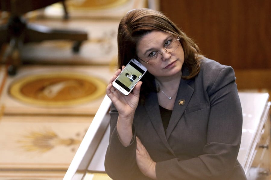FILE - In this March 3, 2016, file photo, Oregon state Sen. Sara Gelser listens to a live stream as members of the House of Representatives finish business before adjourning the 2016 legislative session at the Oregon State Capitol in Salem, Ore. Oregon lawmakers including Gelser are demanding answers from the state’s child welfare agency after a report that a 9-year-old girl in foster care was sent to a Montana facility for six months and injected with Benadryl to control her behavior. A legislative hearing Thursday, April 11, 2019 largely focused on the news report this week by Oregon Public Broadcasting that also revealed caseworkers didn’t visit the girl for months.