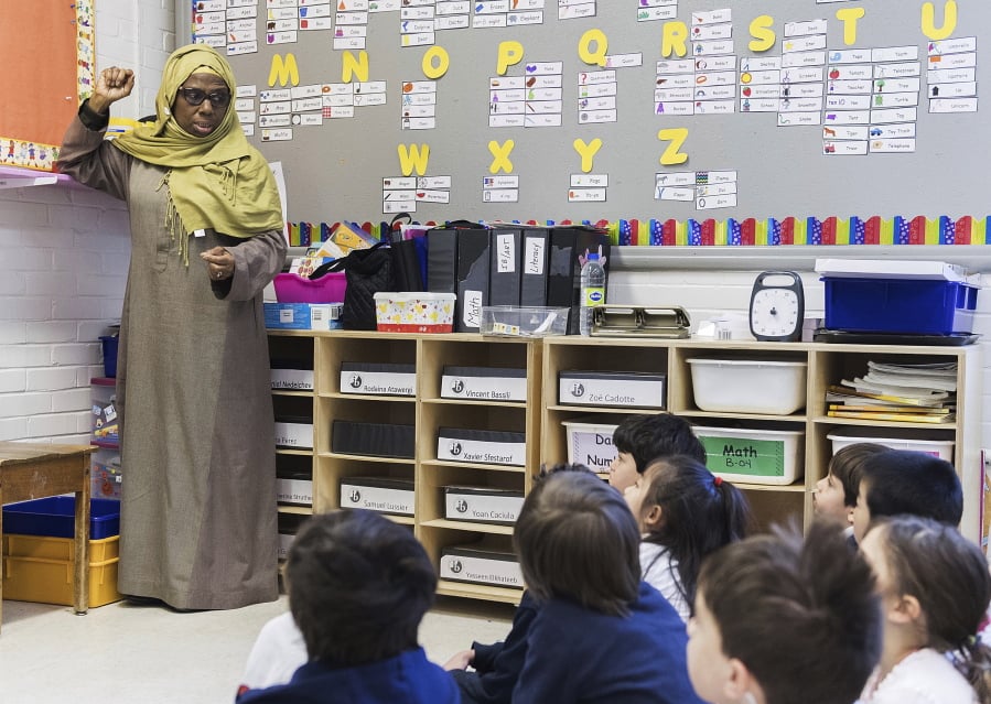 In this Thursday, April 4, 2019, photo, kindergarten teacher Haniyfa Scott gives a lesson during class in Montreal. The Quebec government’s Bill 21 bans the wearing of religious symbols for new government placed employees within schools, the courts and law enforcement.