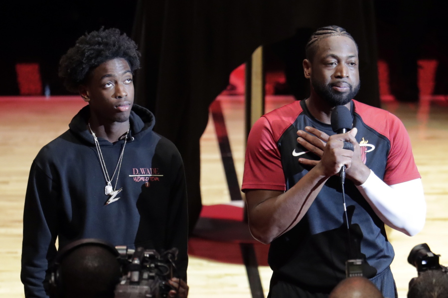 Miami Heat guard Dwyane Wade, right, speaks as his son Zaire, left, looks on during a ceremony honoring Wade who is playing his final home regular season game when the Heat host the Philadelphia 76ers, Tuesday, April 9, 2019, in Miami. Wade is retiring at the end of the season.