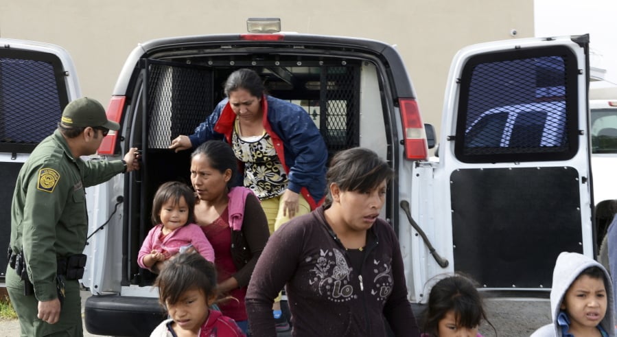 In this Friday, April 12, 2019 photo, a U.S. Border Patrol agent helps migrants out of a van at the Gospel Rescue Mission in Las Cruces, N.M. The U.S. Border Patrol agents dropped off asylum-seeking migrants in New Mexico’s second most populous city for the second day in a row Saturday, April 13, 2019 prompting Las Cruces city officials to appeal for donations of food and personal hygiene items.