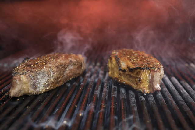 This Nov. 27, 2018 file photo shows steaks on a grill at a restaurant in New York. The idea behind the low-carb diet is that the body enters a ketogenic, fat-burning state when it runs out of the blood sugar that’s fueled by carbs. Still, many nutrition experts say sticking to a low-carb diet is hard, and not everyone is convinced it should be added to the dietary guidelines.