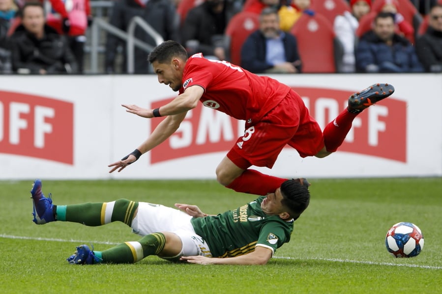 Toronto FC midfielder Marky Delgado (8) dives over Portland Timbers defender Jorge Moreira (2) as the two collide during the first half in Toronto, Saturday.