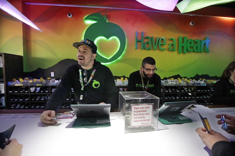 Employees Dan Giroux, left, and Dustin Barrington ring up sales for customers at a marijuana shop in Seattle. When Washington and Colorado launched their pioneering marijuana industries in the face of U.S. government prohibition, they imposed strict rules in hopes of keeping the U.S. Justice Department at bay. Five years later, federal authorities have stayed away, but the industry says it has been stifled by over-regulation. Lawmakers in both states have heard the complaints and are moving to ease the rules.
