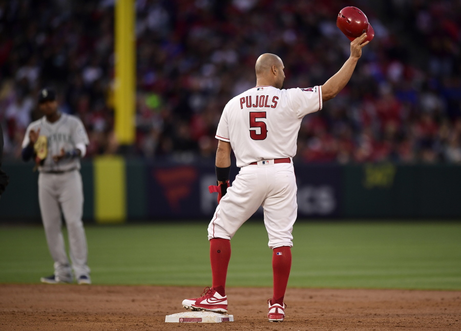Los Angeles Angels’ Albert Pujols, right, tips his helmet to fans after hitting an RBI double as Seattle Mariners shortstop Tim Beckham claps during the third inning of a baseball game Saturday, April 20, 2019, in Anaheim, Calif. With that RBI, Pujols tied Babe Ruth for 5th place on the all-time RBI list with 1,992. (AP Photo/Mark J.