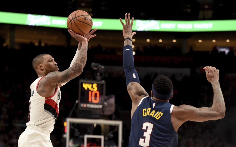 Portland Trail Blazers guard Damian Lillard, left, scores over Denver Nuggets forward Torrey Craig during the second half of an NBA basketball game in Portland, Ore., Sunday, April 7, 2019. The Blazers won 115-108.